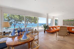 En matplats med ett bord dukat för fyra personer, en soffa och utsikt över havet.