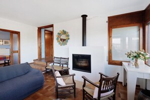 A living room with a sofa, chairs, a fireplace, and a dining area with a table and chairs.