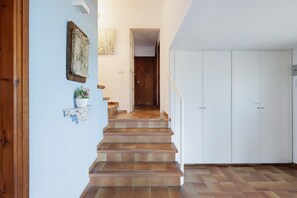 A staircase leading to a room with a wardrobe, a small shelf with a vase, and a wall-mounted sculpture.