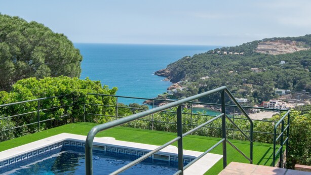 Una piscina con vista sul mare, immersa nel verde e su una collina.
