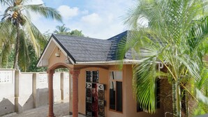 A small building with a tiled roof, a porch with a column, and a gate.