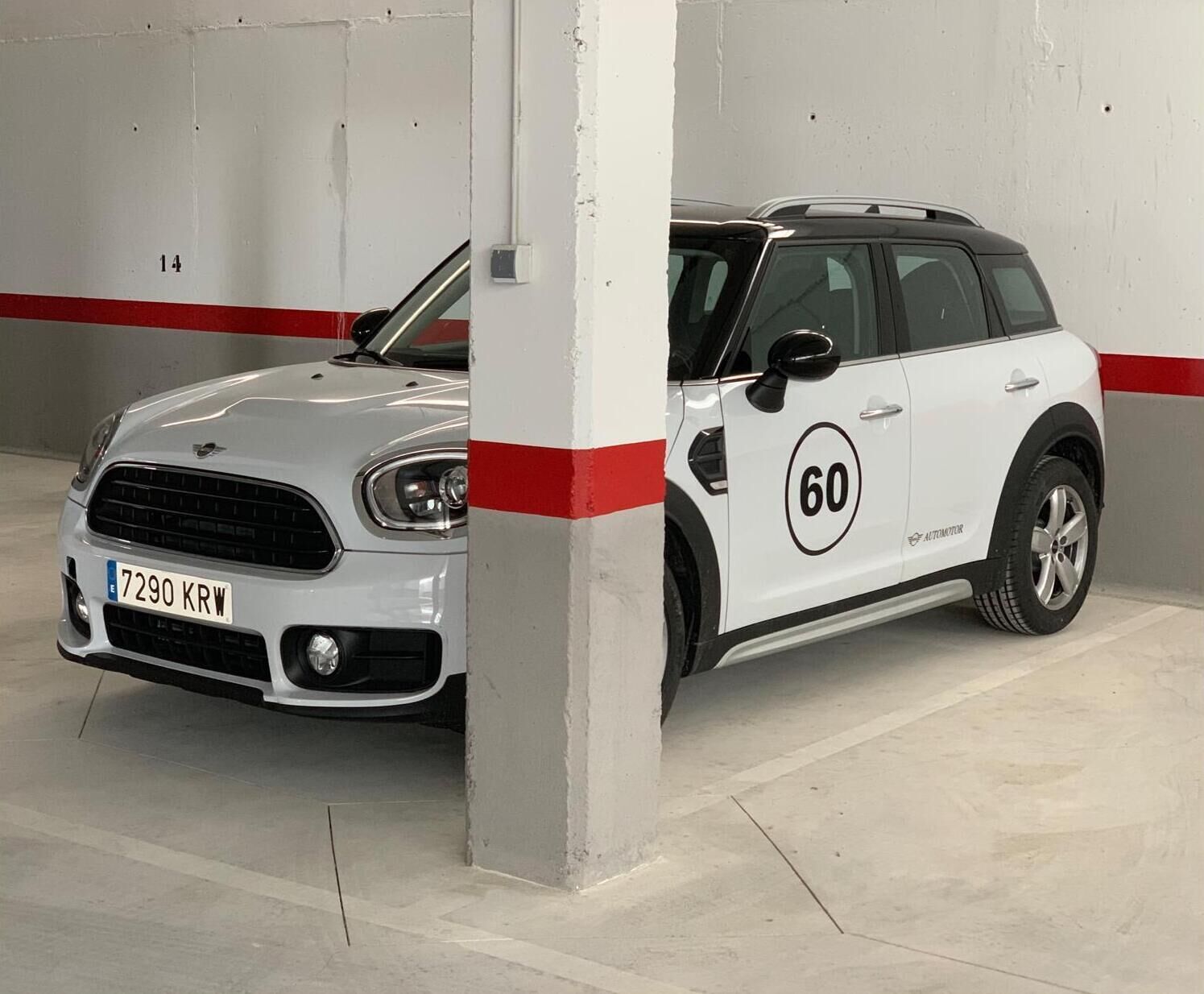Ein weißer Mini Cooper mit der Nummer 60 steht in einer Garage.