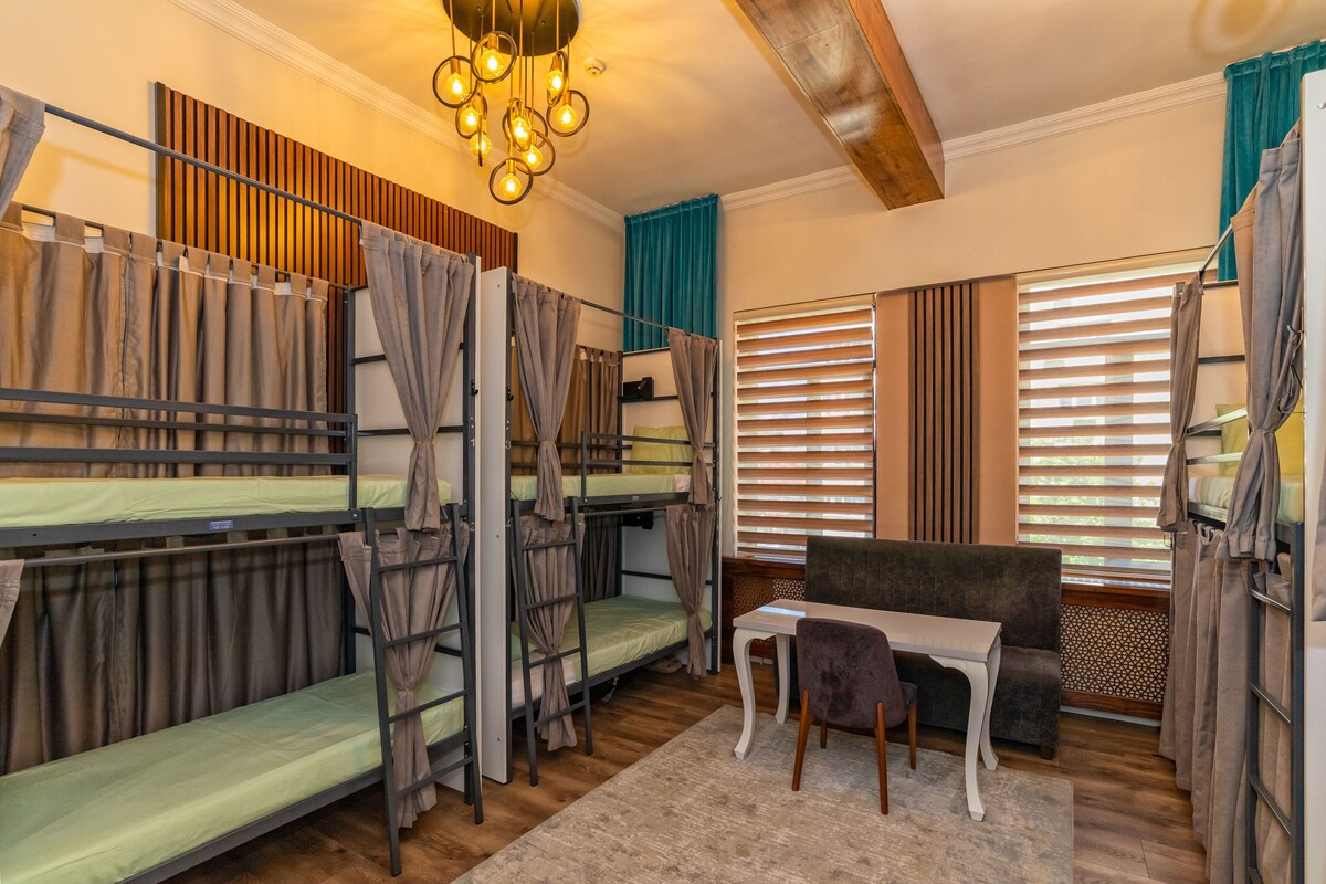 A dormitory room with bunk beds, a table, and a couch.