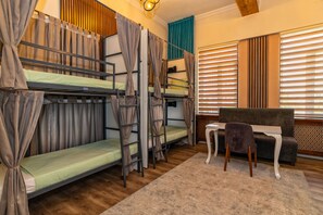Une chambre de dortoir avec des lits superposés, une petite table et un canapé.