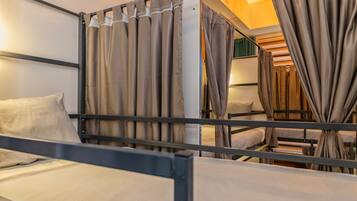Een slaapkamer met stapelbedden, gordijnen, een bed en een hoofdbord.