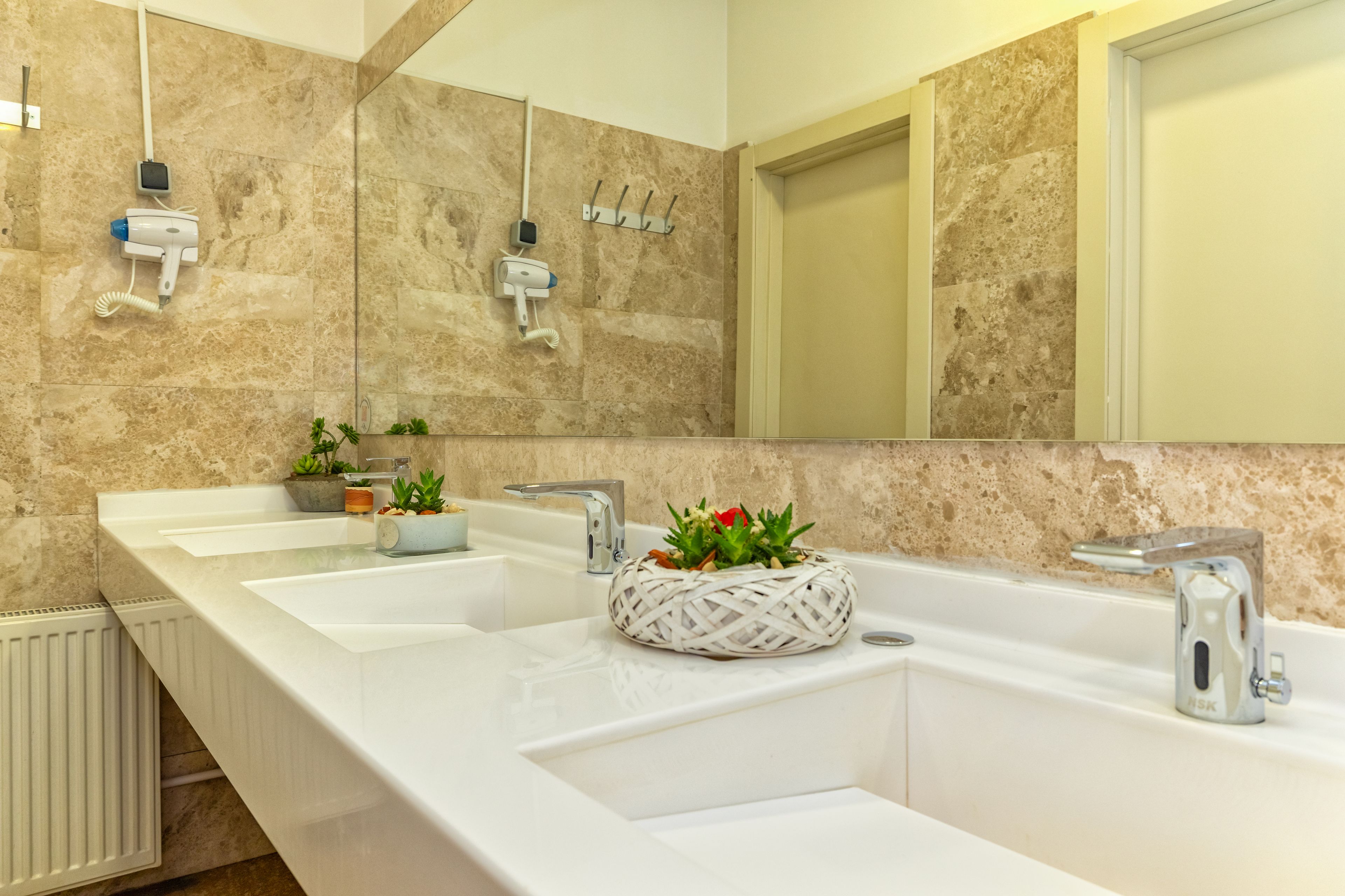 Une salle de bain avec deux lavabos, un miroir et un sèche-cheveux fixé au mur.
