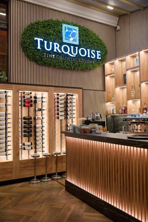 Un interior de restaurante con un cartel que dice 'Turquoise Fine Oriental Cuisine', paneles de madera y una vitrina de vinos.