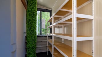 A room with white shelving units, a green vertical garden, and a window with a view of trees.