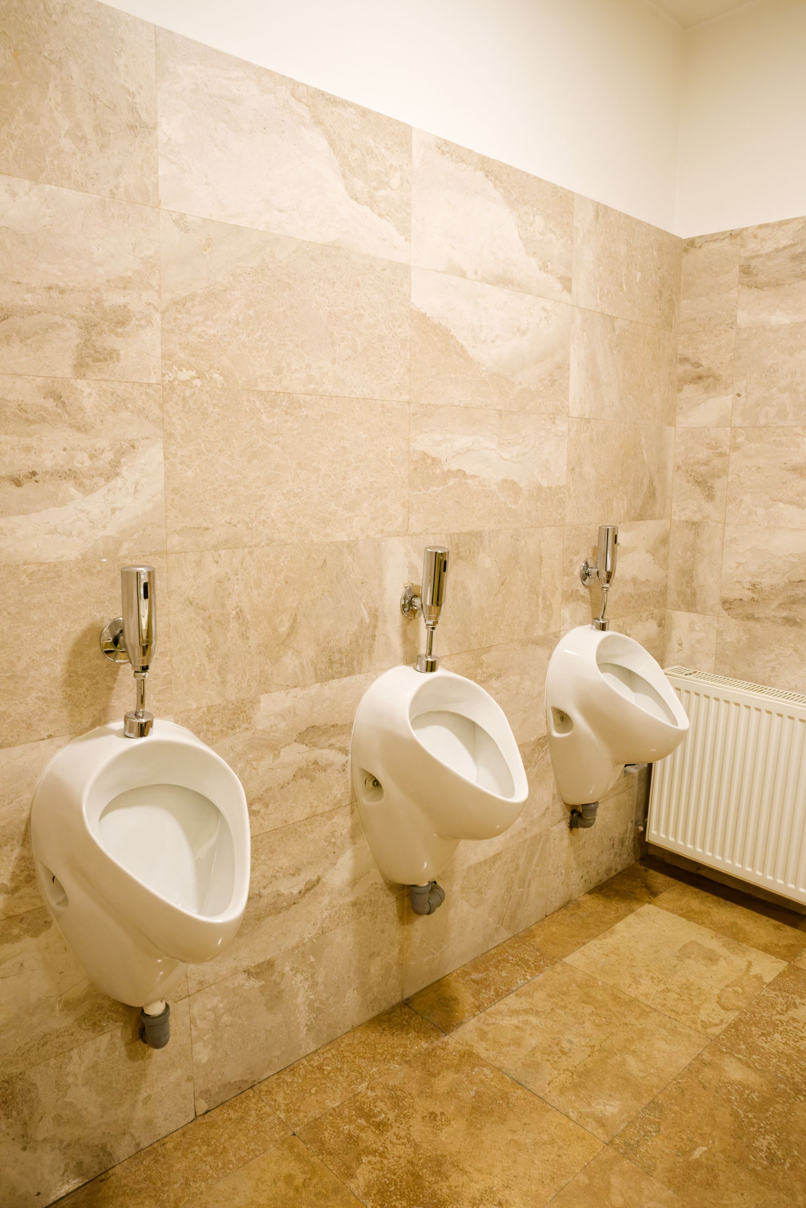 Un baño con tres orinales adosados a una pared de azulejos.