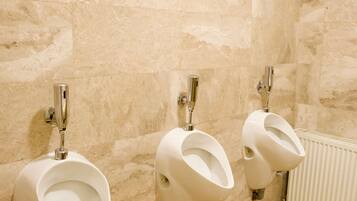 Un baño con tres orinales adosados a una pared de azulejos.