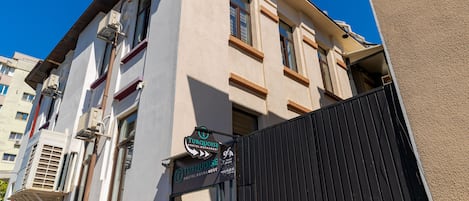 A building with a sign for 'Turquoise Hostel Bucharest' and a gated entrance.