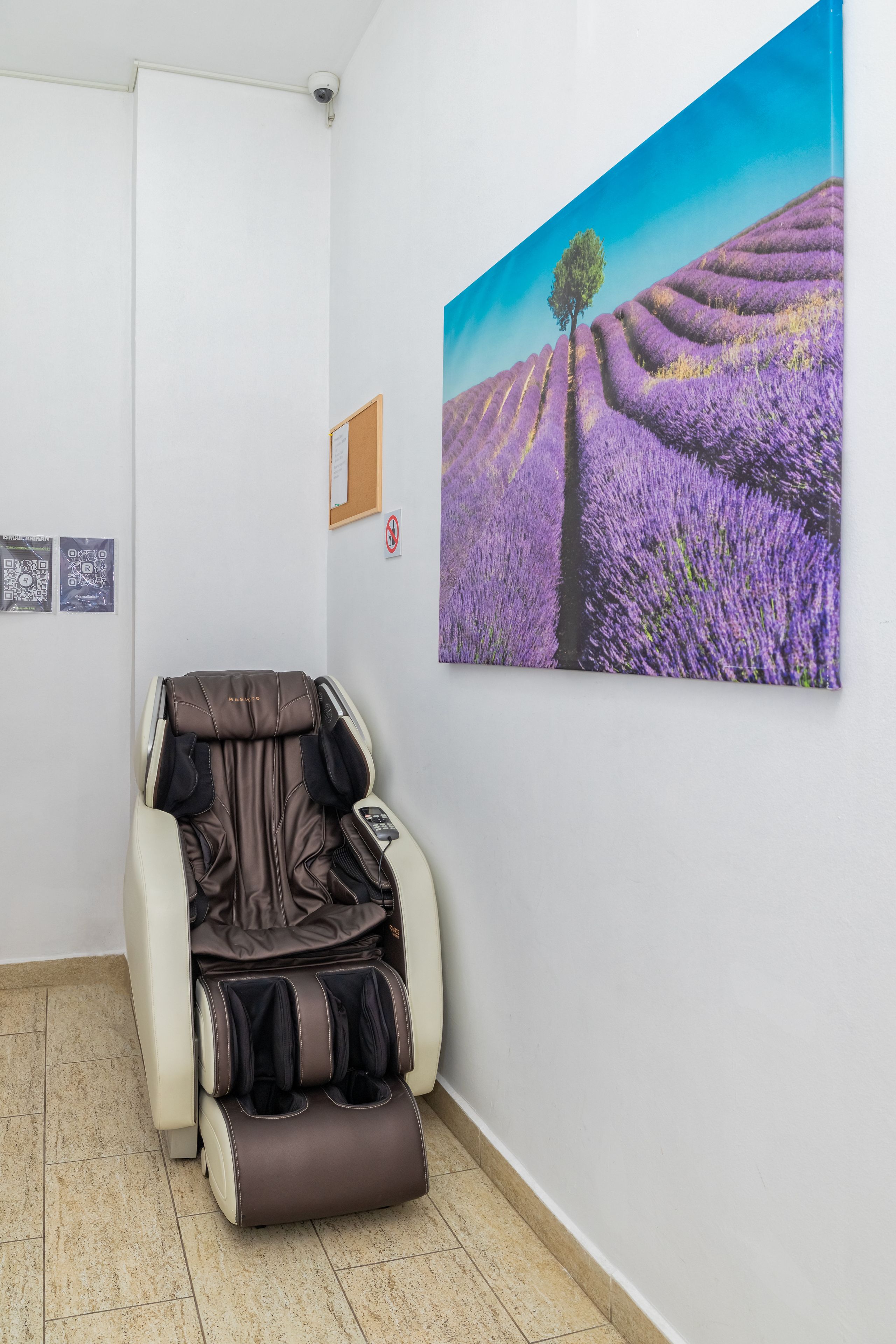 Un fauteuil de massage dans une pièce dont le mur est orné d’un tableau représentant un champ de lavande.
