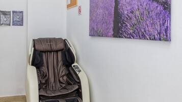 Un fauteuil de massage dans une pièce dont le mur est orné d’un tableau représentant un champ de lavande.