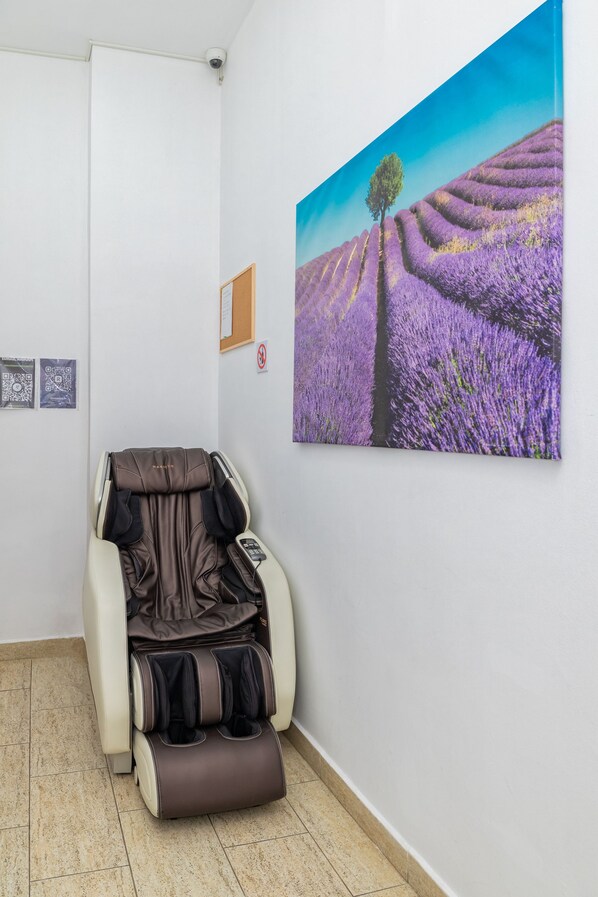 A massage chair in a room with a lavender field painting on the wall. - TURQUOISE HOSTEL (Bucharest)