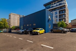 A parking lot with multiple cars, a blue building, and residential buildings in the background. - TURQUOISE HOSTEL (Bucharest)