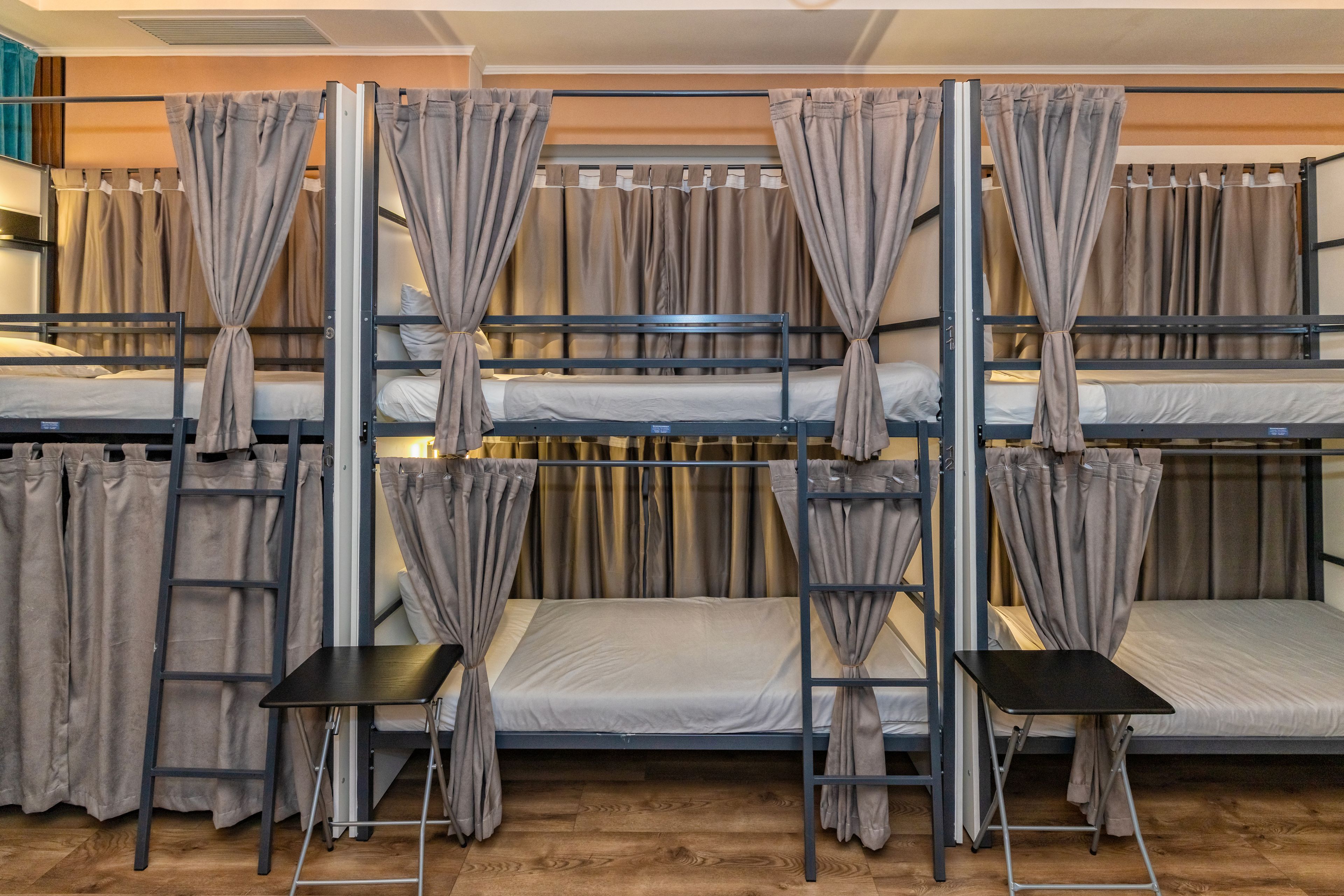 A bunk bed room with curtains, a desk, and a chair.