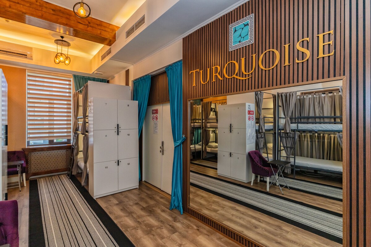 A hotel room with a wooden wall, a large mirror reflecting the room, and a sign that reads 'Turquoise'.