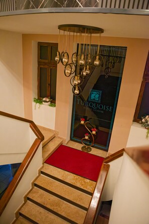 A staircase with a red carpet leading to a room with a sign reading 'Turquoise World Cuisine'. - TURQUOISE HOSTEL (Bucharest)