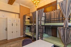 Une chambre de dortoir équipée de lits superposés, d’un bureau, d’une chaise, d’une armoire et d’un luminaire au plafond.