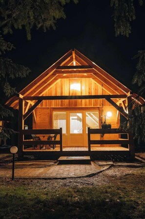 Una cabaña de madera con porche, una puerta y una ventana.