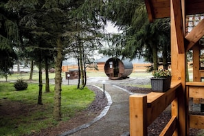 Una cabaña de madera con un sendero que lleva a una gran estructura en forma de barril, rodeada de árboles.