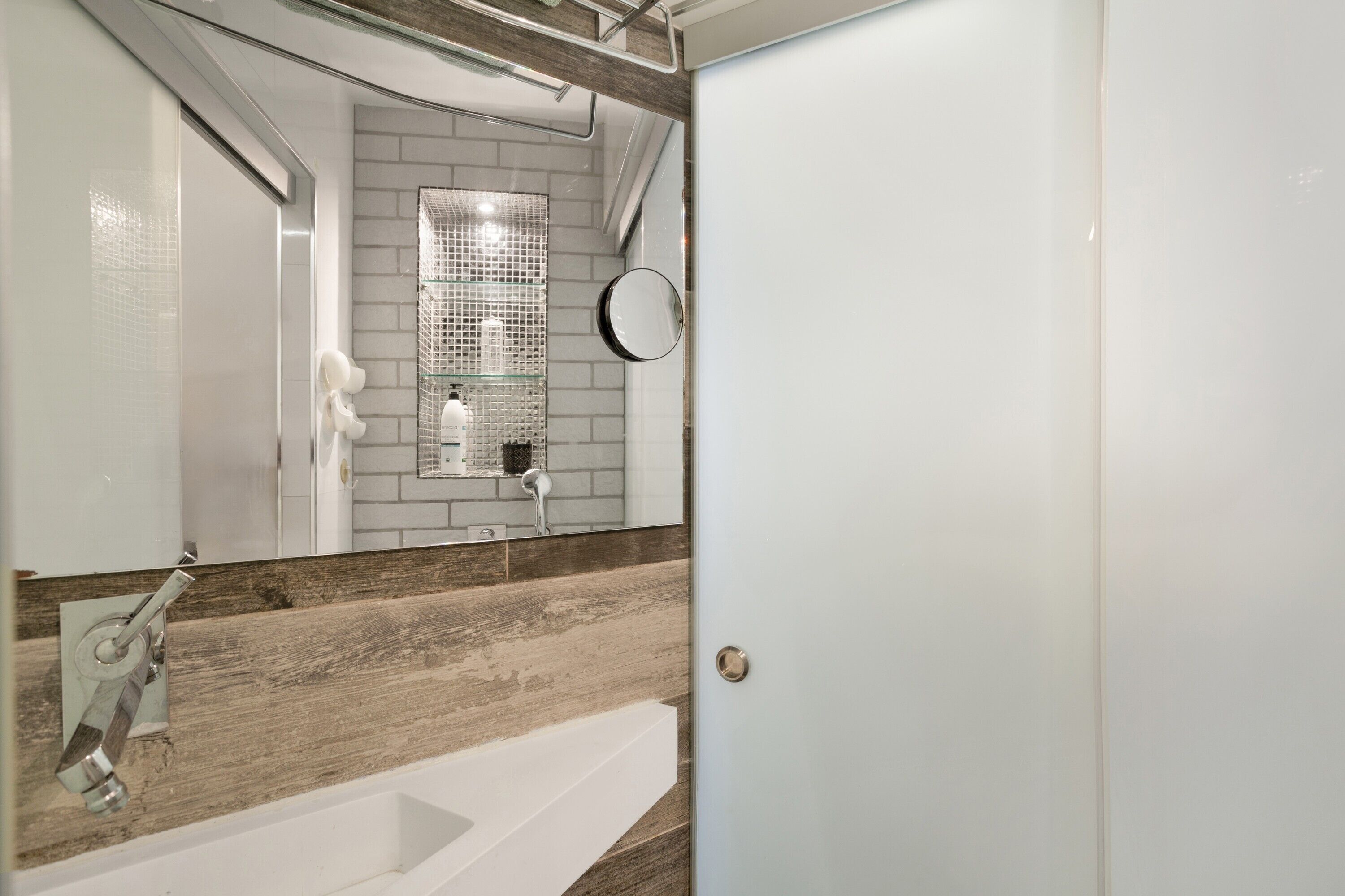A bathroom with a white bathtub, a mirror, and a shower area with a tiled wall.