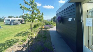 Ein Gebäude mit Gartenanlage, einem Weg und einem abgestellten Wohnmobil.