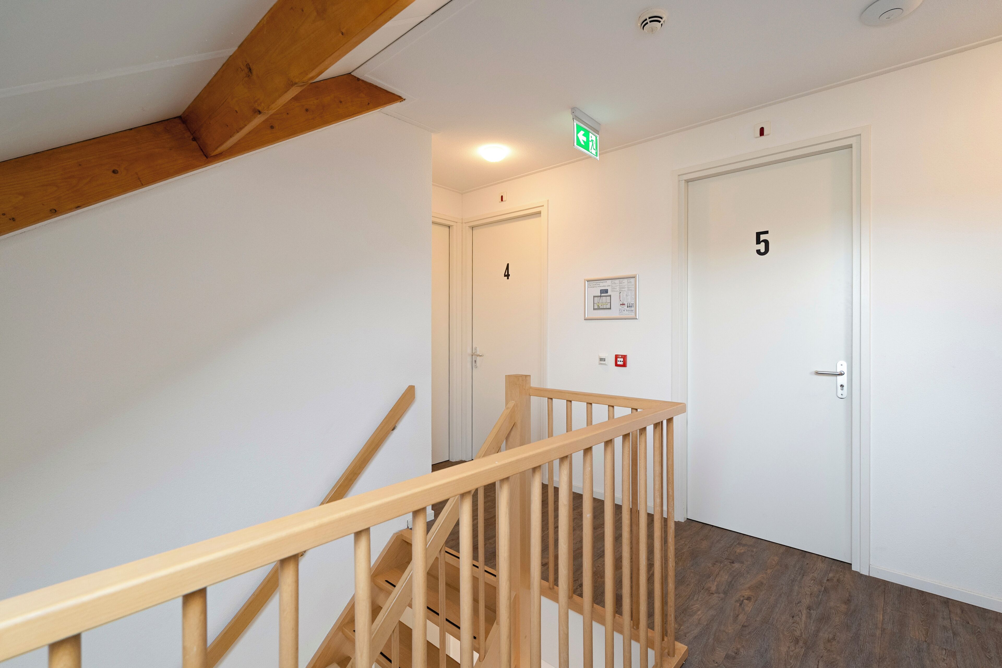 A wooden staircase with a handrail leading to a door marked with the number 5.