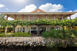 A building with a covered patio, stone wall, and a water feature in front. - peaceful Garden Villa - Private Pool (Jan Thiel)