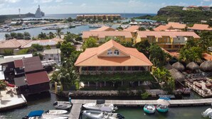 Un hotel costero con un muelle, barcos y vistas al mar.