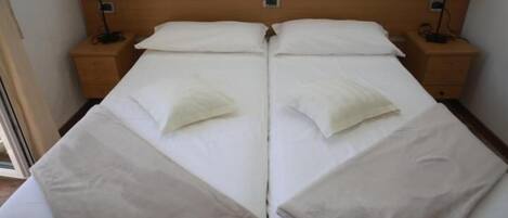 A double bed with two nightstands, each with a lamp, in a room with a wooden headboard.