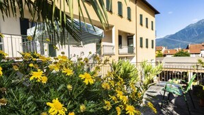 Un bâtiment doté de balcons, une montagne en arrière-plan et des fleurs jaunes au premier plan.