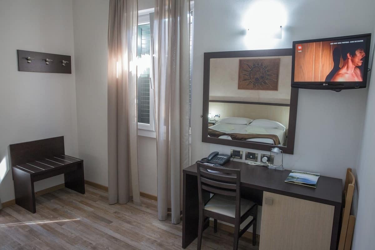 Una habitación de hotel con escritorio, silla y televisor montado en la pared.