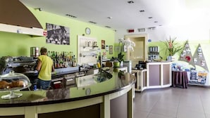 Un espace bar avec un comptoir, des étagères remplies de bouteilles, une horloge et une plante.