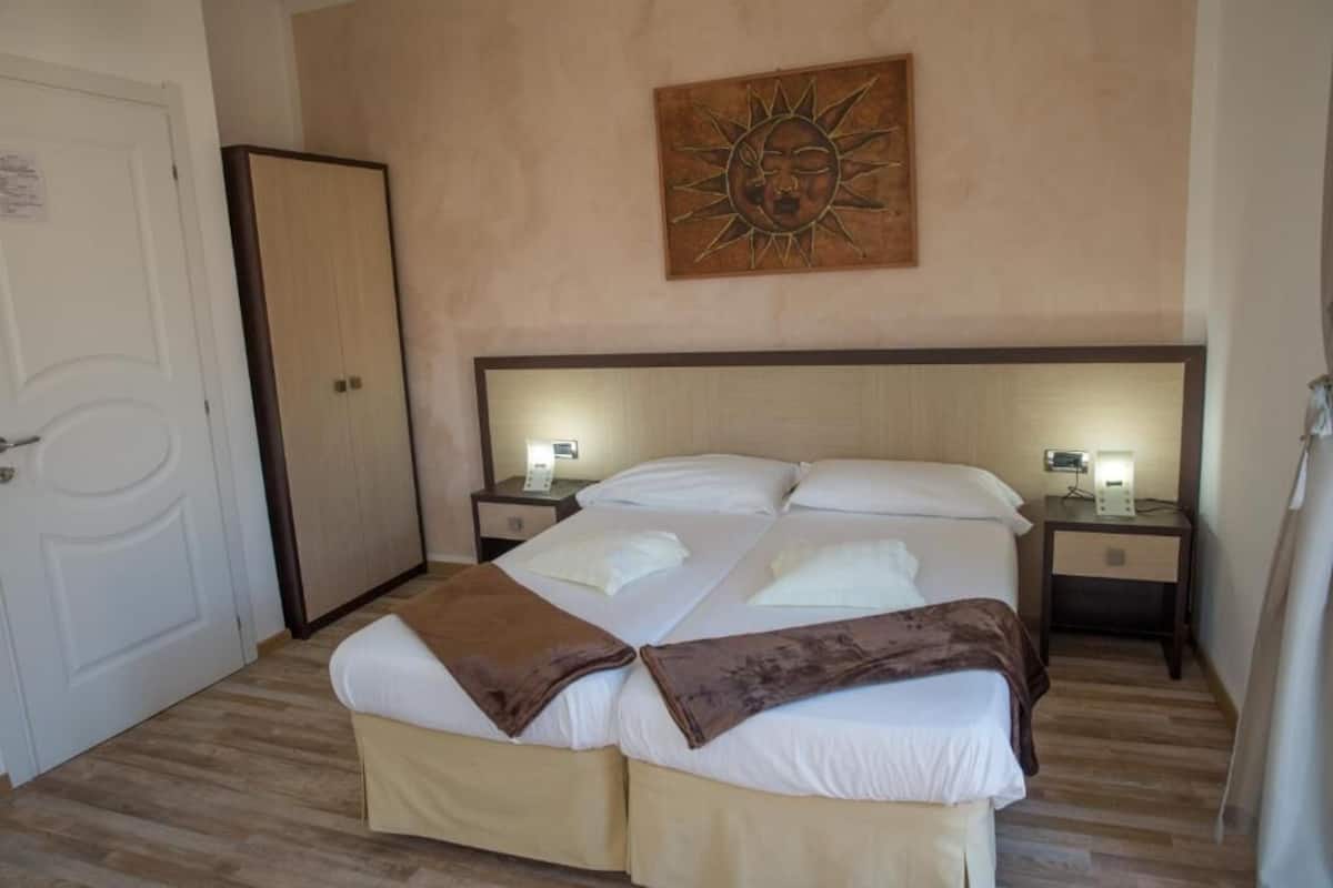 Una cama doble con dos mesitas de noche, un armario y una obra de arte colgada en la pared.