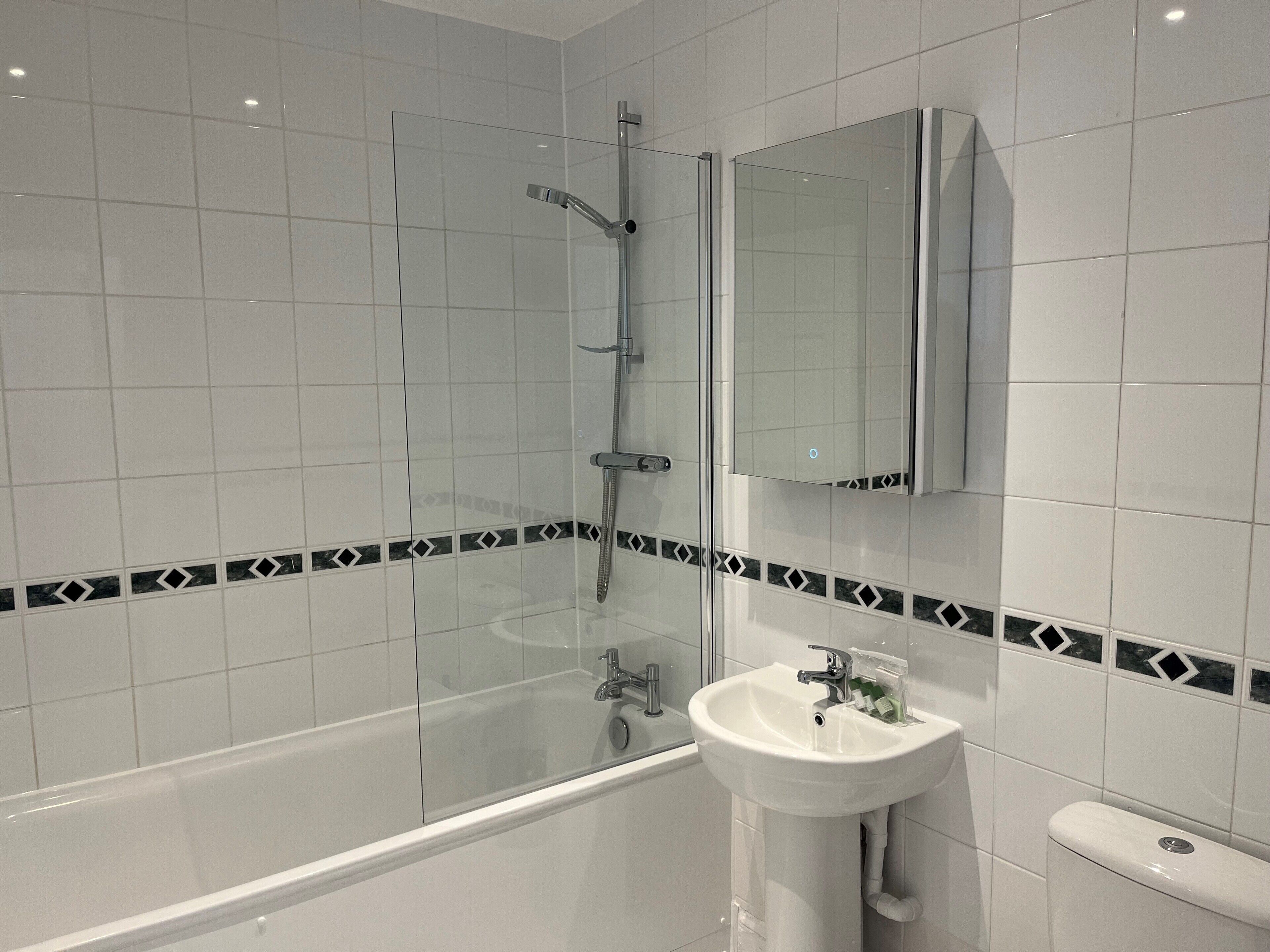 A modern bathroom with a glass-enclosed shower, a white sink, and a mirror above the sink.