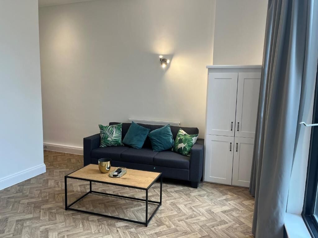 A living room with a sofa, a coffee table, a cabinet, and a wall-mounted light fixture.