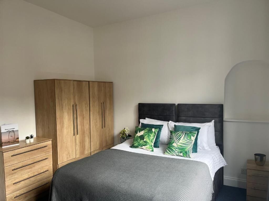 Une chambre à coucher avec un lit, une armoire en bois et une table de chevet.