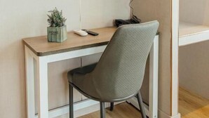 A modern room with a mounted TV displaying a sports channel, a desk with a chair, a small plant, and a power outlet. - HOTEL GOLDEN (San Sebastián de los Reyes)