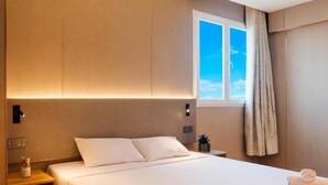 A hotel room with a large bed, a nightstand, a window with curtains, and a wall-mounted light. - HOTEL GOLDEN (San Sebastián de los Reyes)