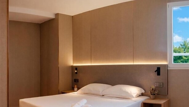A modern bedroom with a bed, nightstands, and a window. - HOTEL GOLDEN (San Sebastián de los Reyes)