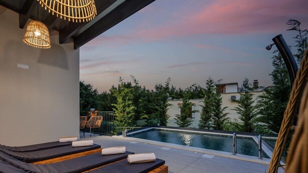 Eine Dachterrasse mit Pool, Liegestühlen und Blick auf Bäume und Gebäude.