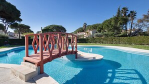 A swimming pool with a wooden bridge, clear blue water, and surrounding greenery. - House Next to Golf Course, 800 m from Platja de Pals (Pals)