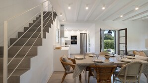 A modern kitchen with stainless steel appliances, a dining area with wicker chairs, and a staircase. - House Next to Golf Course, 800 m from Platja de Pals (Pals)
