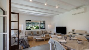 A modern living room with a sofa, coffee table, dining table, and a TV. - House Next to Golf Course, 800 m from Platja de Pals (Pals)