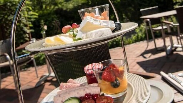Een drijvende etagère buiten met eten en drinken, een toren op de achtergrond en buitenmeubilair.