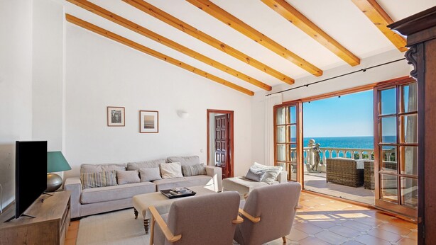 A living room with a sofa, armchairs, a coffee table, and a TV. There is a balcony with a view of the sea. - Fantastic Villa with Pool and Spectacular Sea Views (Sa Riera)