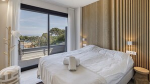 Ein Hotelzimmer mit einem großen Bett, Blick ins Freie, einer Holzvertäfelung und einem Nachttisch.