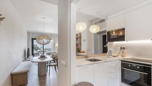 Eine moderne Küche mit weißen Schränken, einem eingebauten Backofen und Pendelleuchten.