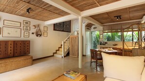 Amplia sala de estar con techos altos, una escalera y un comedor con luz natural.